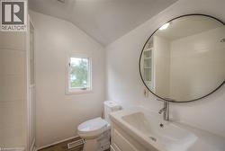 Bathroom with vanity, vaulted ceiling, and dark wood-style floors - 