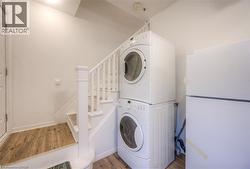 Laundry area featuring stacked washing machine and dryer and light wood-style floors - 