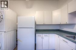 Kitchen with freestanding refrigerator, dark countertops, and white cabinetry - 