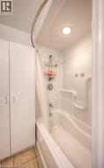 Bathroom with light tile patterned floors and shower / tub combo with curtain - 