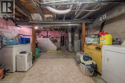 Unfinished basement featuring washer / clothes dryer, white refrigerator, and heating unit - 