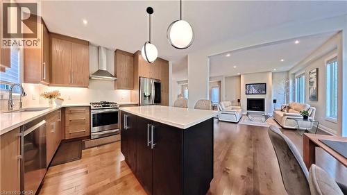 Kitchen with open floor plan, stainless steel appliances, light wood-style flooring, modern cabinets, and decorative light fixtures - 63 Ian Ormston Drive, Kitchener, ON - Indoor Photo Showing Kitchen With Upgraded Kitchen