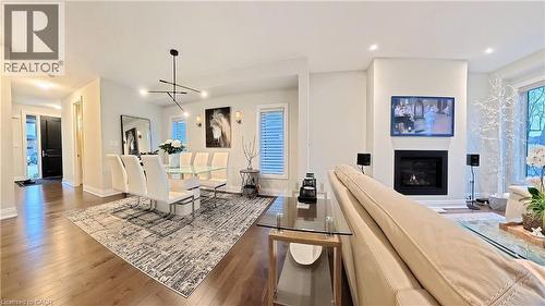 Kitchen with open floor plan, hardwood / wood-style floors, a glass covered fireplace, and healthy amount of natural light - 63 Ian Ormston Drive, Kitchener, ON - Indoor Photo Showing Other Room With Fireplace