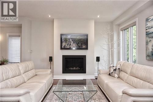 Living room featuring a glass covered fireplace, wood finished floors, and recessed lighting - 63 Ian Ormston Drive, Kitchener, ON - Indoor Photo Showing Living Room With Fireplace