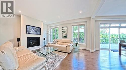 Living room featuring hardwood / wood-style flooring, a glass covered fireplace, and recessed lighting - 63 Ian Ormston Drive, Kitchener, ON - Indoor Photo Showing Living Room With Fireplace