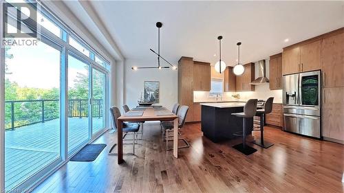 Kitchen featuring stainless steel refrigerator with ice dispenser, a center island, light wood-style floors, hanging light fixtures, and a kitchen breakfast bar - 63 Ian Ormston Drive, Kitchener, ON - Indoor Photo Showing Other Room