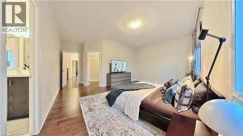 Bedroom featuring a walk in closet, light wood-type flooring, and a textured ceiling - 63 Ian Ormston Drive, Kitchener, ON - Indoor Photo Showing Bedroom
