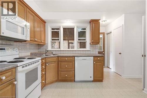 Kitchen featuring white appliances, decorative backsplash, wood finish cabinets, recessed lighting, and light floors - 890 Falcon Boulevard, Burlington, ON - Indoor Photo Showing Kitchen With Double Sink