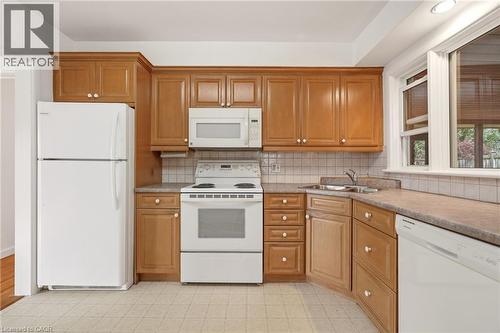 Kitchen featuring white appliances, wood finish cabinets, light countertops, and decorative backsplash - 890 Falcon Boulevard, Burlington, ON - Indoor Photo Showing Kitchen With Double Sink