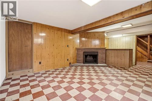 Unfurnished living room with a brick fireplace, light flooring, wooden walls, and beamed ceiling - 890 Falcon Boulevard, Burlington, ON - Indoor With Fireplace