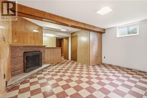 Basement featuring a fireplace, light flooring, and wood walls - 890 Falcon Boulevard, Burlington, ON - Indoor Photo Showing Other Room With Fireplace