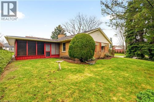View of front of property with a front lawn, a chimney, a sunroom, and brick siding - 890 Falcon Boulevard, Burlington, ON - Outdoor