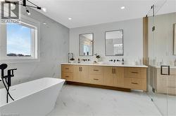 Bathroom featuring double vanity, a soaking tub, light marble finish flooring, a stall shower, and stone wall - 