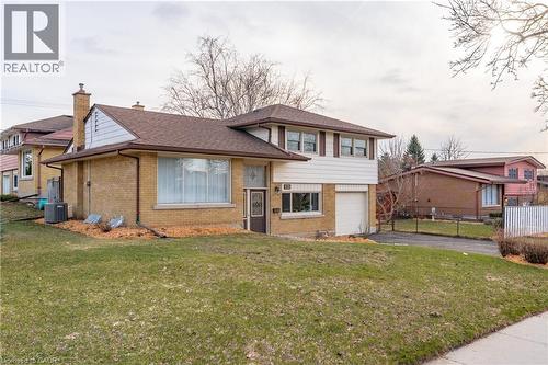 Split level home with asphalt driveway, brick siding, an attached garage, a shingled roof, and a chimney - 135 Burbank Road, Kitchener, ON - Outdoor