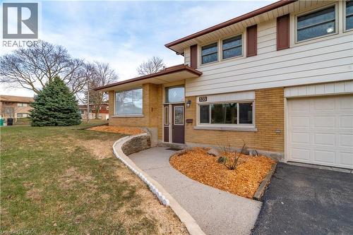 View of front facade with brick siding, a front yard, a garage, and asphalt driveway - 135 Burbank Road, Kitchener, ON - Outdoor