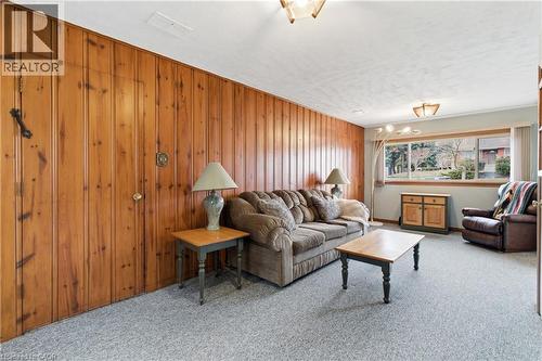 Family room featuring light coloured carpet, wood walls, and a textured ceiling - 135 Burbank Road, Kitchener, ON - Indoor Photo Showing Living Room