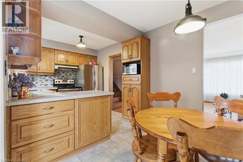 Kitchen with light countertops, a peninsula, stainless steel appliances, backsplash, and decorative light fixtures - 135 Burbank Road, Kitchener, ON - Indoor