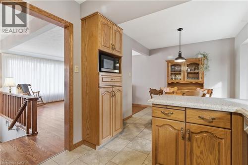 Kitchen featuring light stone countertops, light tile patterned floors, decorative light fixtures, and built in microwave - 135 Burbank Road, Kitchener, ON - Indoor Photo Showing Kitchen