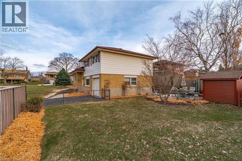 Rear view of property featuring a fenced backyard, an attached garage, brick siding, and a shed - 135 Burbank Road, Kitchener, ON - Outdoor