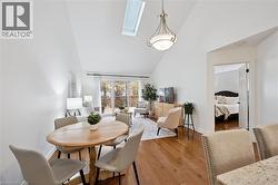 Dining room with a skylight, high vaulted ceiling, and hardwood / wood-style floors - 