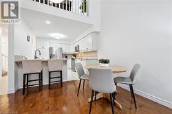 Dining area with light wood-type flooring, a high ceiling, and stairway - 