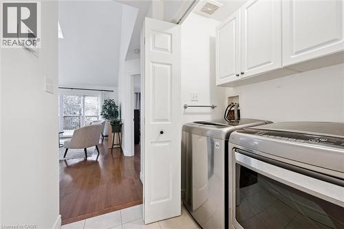 Laundry room featuring separate washer and dryer, cabinet space, high vaulted ceiling, and light tile patterned flooring - 92 Schroder Crescent, Guelph, ON - Indoor Photo Showing Laundry Room