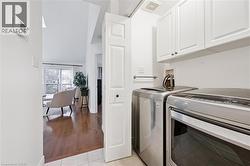 Laundry room featuring separate washer and dryer, cabinet space, high vaulted ceiling, and light tile patterned flooring - 