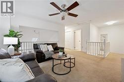 Living area with light carpet, attic access, and a ceiling fan - 