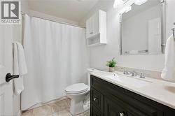 Bathroom with a shower with shower curtain, vanity, and light tile patterned floors - 
