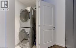 Laundry room with estacked washer and dryer and wood finished floors - 