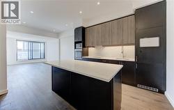 Kitchen with dark cabinetry, light stone counters, stainless steel appliances, a kitchen island, and recessed lighting - 