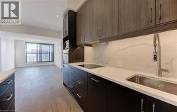 Kitchen with light stone countertops, light wood-style flooring, oven, decorative backsplash, and recessed lighting - 