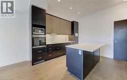 Kitchen with stainless steel appliances, decorative backsplash, light wood-type flooring, modern cabinets, and a kitchen island - 