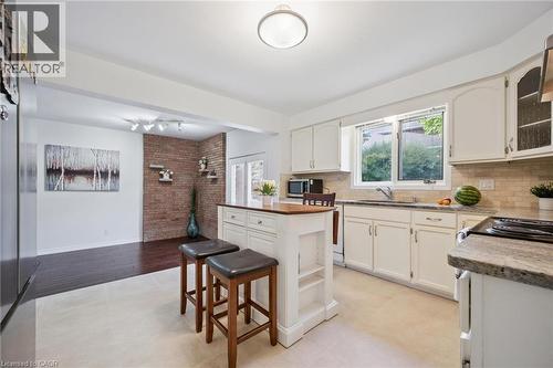 Kitchen with stainless steel appliances, tasteful backsplash, a center island, glass insert cabinets, and a breakfast bar - 599 Beechwood Drive, Waterloo, ON - Indoor Photo Showing Kitchen