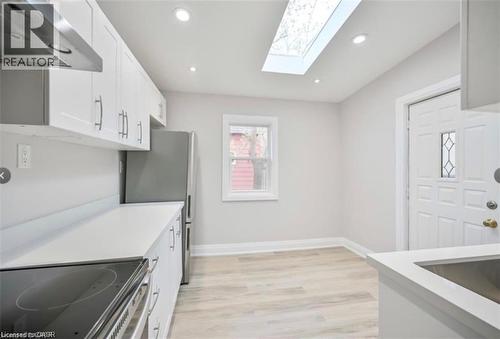 Kitchen featuring ventilation hood, white cabinets, light wood-type flooring, recessed lighting, and stainless steel appliances - 1024 Cannon Street E, Hamilton, ON - Indoor Photo Showing Kitchen