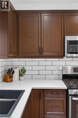 Kitchen with stainless steel appliances, tasteful backsplash, and dark wood finish cabinetry - 248 London Street S, Hamilton, ON - Indoor Photo Showing Kitchen With Double Sink