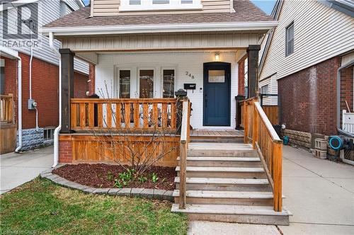 Entrance to property featuring a shingled roof, a porch, and brick siding - 248 London Street S, Hamilton, ON - Outdoor With Exterior