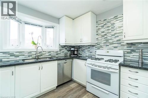 Kitchen with white gas range, dark stone counters, white cabinets, and dishwasher - 1492 Sandgate Crescent Unit# Upper, Mississauga, ON - Indoor Photo Showing Kitchen With Double Sink