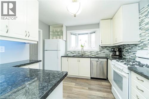 Kitchen with white appliances, white cabinetry, light wood-style floors, dark stone counters, and tasteful backsplash - 1492 Sandgate Crescent Unit# Upper, Mississauga, ON - Indoor Photo Showing Kitchen With Upgraded Kitchen