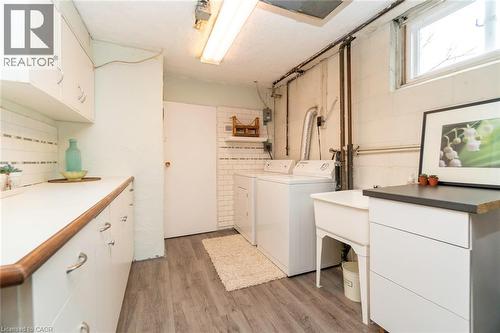 Laundry area featuring cabinet space, light wood-style flooring, independent washer and dryer, and concrete block wall - 1492 Sandgate Crescent Unit# Upper, Mississauga, ON - Indoor Photo Showing Laundry Room