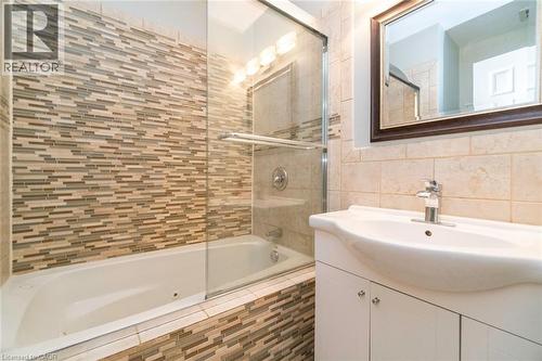 Bathroom with vanity, tile walls, a combined bath / shower with jetted tub, and decorative backsplash - 1492 Sandgate Crescent Unit# Upper, Mississauga, ON - Indoor Photo Showing Bathroom