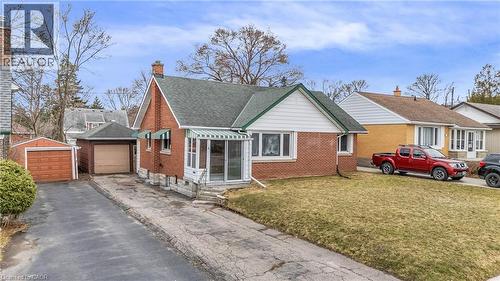 Bungalow-style home featuring a front lawn, brick siding, a garage, a chimney, and driveway - 41 Floral Crescent, Kitchener, ON - Outdoor