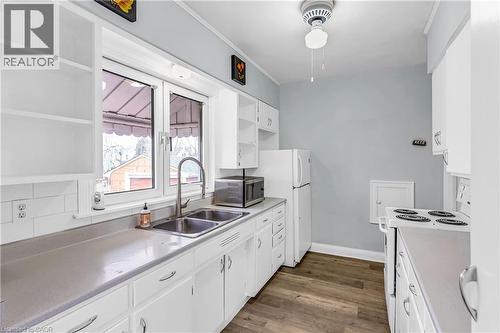 Kitchen featuring white electric range oven, white cabinetry, open shelves, light countertops, and stainless steel microwave - 41 Floral Crescent, Kitchener, ON - Indoor Photo Showing Kitchen With Double Sink