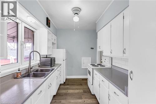 Kitchen featuring white electric stove, white cabinets, dark wood finished floors, ornamental molding, and stainless steel countertops - 41 Floral Crescent, Kitchener, ON - Indoor Photo Showing Kitchen With Double Sink