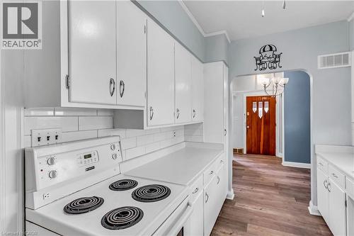 Kitchen with electric stove, white cabinetry, light countertops, arched walkways, and light wood-type flooring - 41 Floral Crescent, Kitchener, ON - Indoor Photo Showing Kitchen