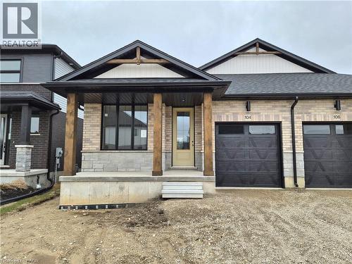 View of front of home with a garage, a porch, driveway, brick siding, and stone siding - 104 Thackeray Way, Harriston, ON - Outdoor With Facade