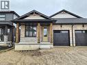 View of front of home with a garage, a porch, driveway, brick siding, and stone siding - 104 Thackeray Way, Harriston, ON  - Outdoor With Facade 