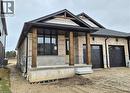 View of front of house with a porch, a garage, stone siding, dirt driveway, and brick siding - 104 Thackeray Way, Harriston, ON  - Outdoor 