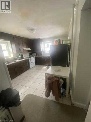 Kitchen with dark wood finish cabinets, freestanding refrigerator, light tile patterned floors, electric stove, and light countertops - 9 Waterloo Avenue, Guelph, ON - Indoor