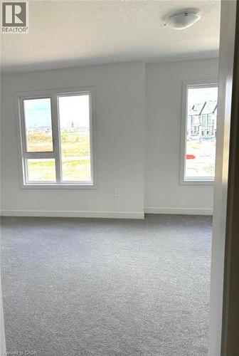 Carpeted empty room with a textured ceiling and baseboards - 7 Pin Oak Common, Cambridge, ON - Indoor Photo Showing Other Room